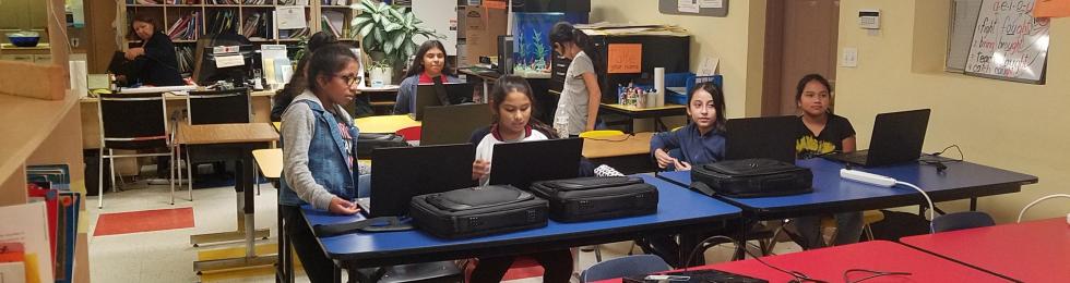 Children in classroom with new laptops.